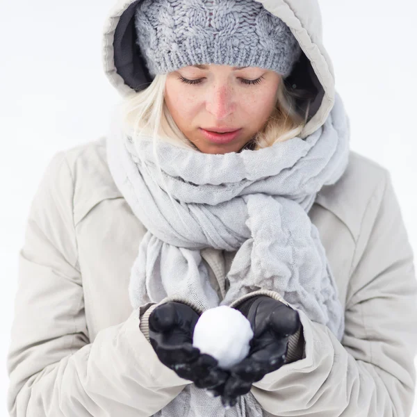 Niña sosteniendo bola de nieve en invierno frío . — Foto de Stock