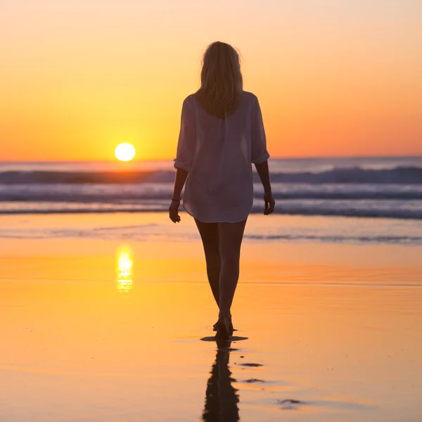 Señora caminando en la playa de arena en la puesta del sol . —  Fotos de Stock