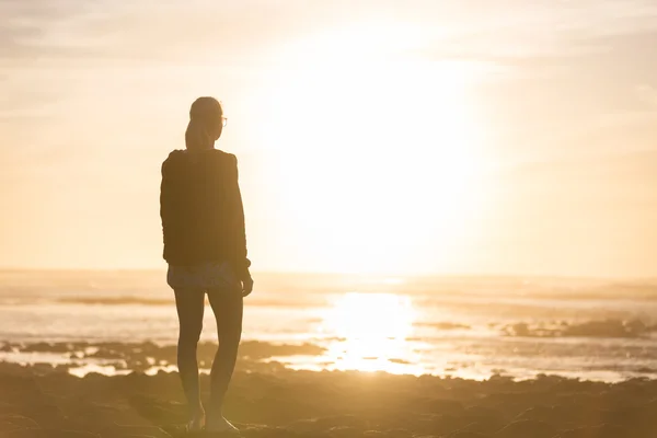 Жінка на піщаному пляжі дивиться захід сонця . — стокове фото