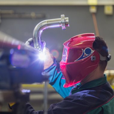Industrial worker welding in metal factory. clipart