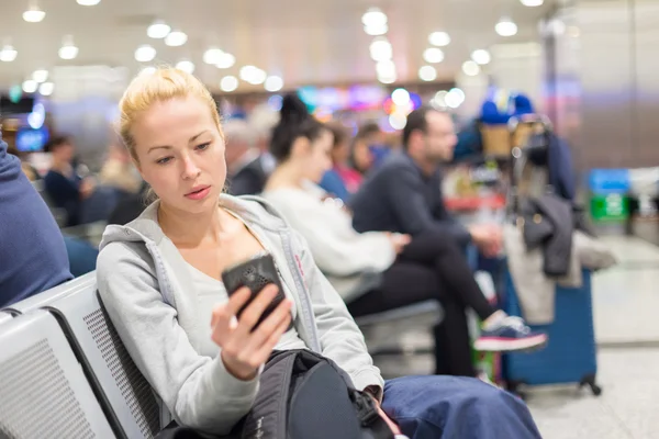 Viaggiatore femminile utilizzando il telefono cellulare durante l'attesa . — Foto Stock