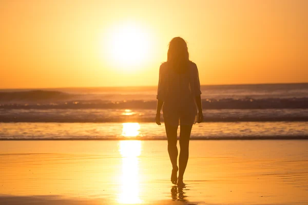 Lady lopen op het zandstrand in de zonsondergang. — Stockfoto