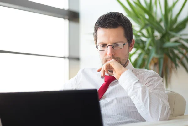 Uomo d'affari in ufficio che legge sul computer portatile . — Foto Stock