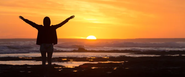 Ingyenes nő élvezi a szabadság tengerparton naplementekor. — Stock Fotó