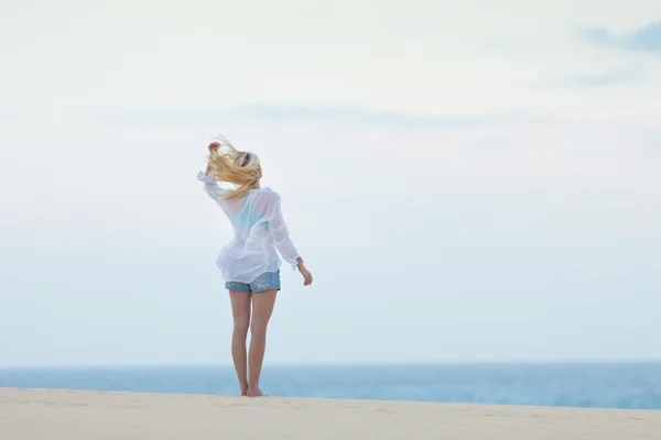 सुबह सफेद शर्ट में रेत समुद्र तट पर महिला . — स्टॉक फ़ोटो, इमेज