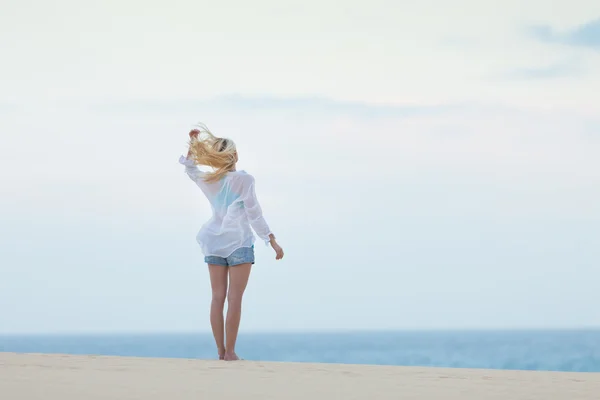 Kvinna på sandstrand i vit skjorta i morgon. — Stockfoto