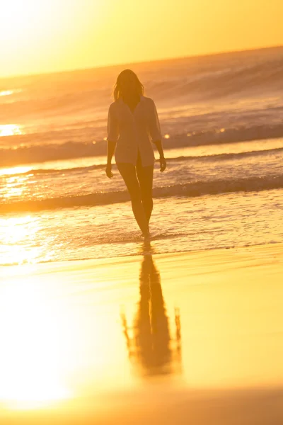 Señora caminando en la playa de arena en la puesta del sol . — Foto de Stock