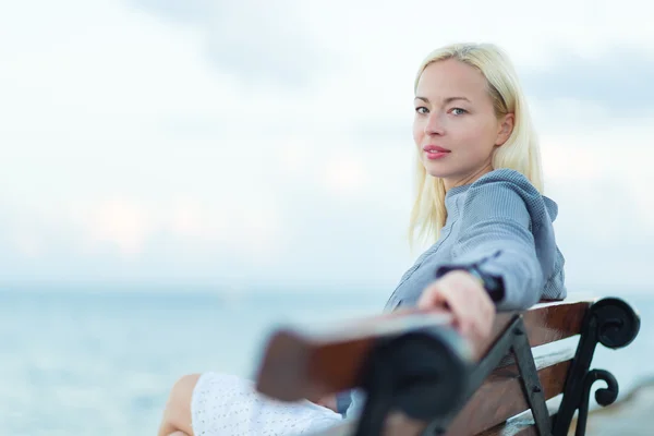 Dam som sitter på en bänk utomhus — Stockfoto