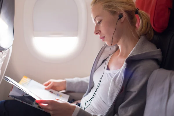 Woman reading magazine on airplane. — Stock Photo, Image