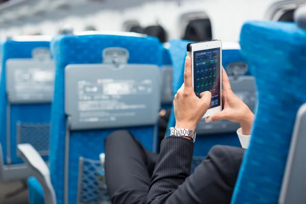 Uomo d'affari che utilizza il telefono tablet sull'aereo . — Foto Stock