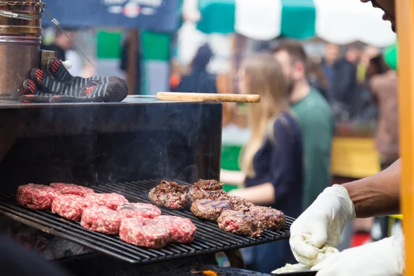 Beef burgers being grilled on food stall grill. — Stock Photo, Image