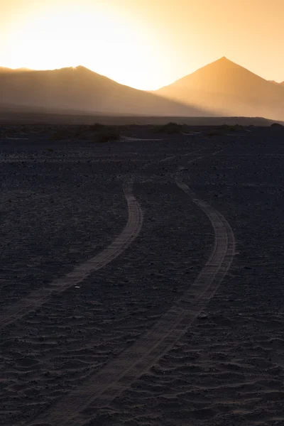 Wheel tracks in sand and dramatic landscape. — Stock Photo, Image