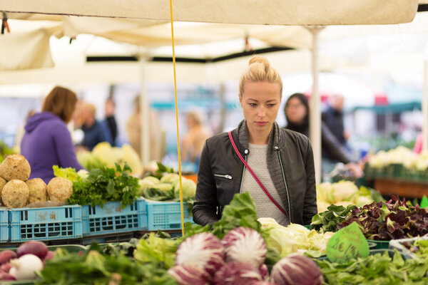 Woman buying vegetable at local food market.