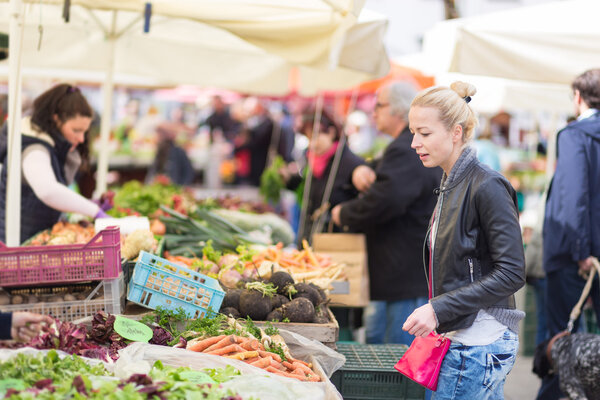 Woman buying vegetable at local food market.