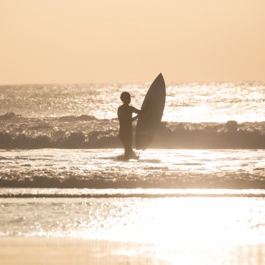 Sörfçü surfboard ile sahilde.