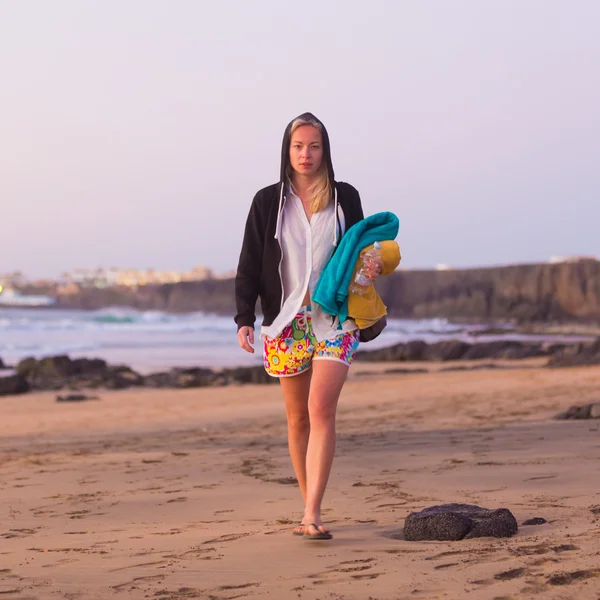 Mujer deportiva caminando en la playa de arena en la puesta del sol . —  Fotos de Stock