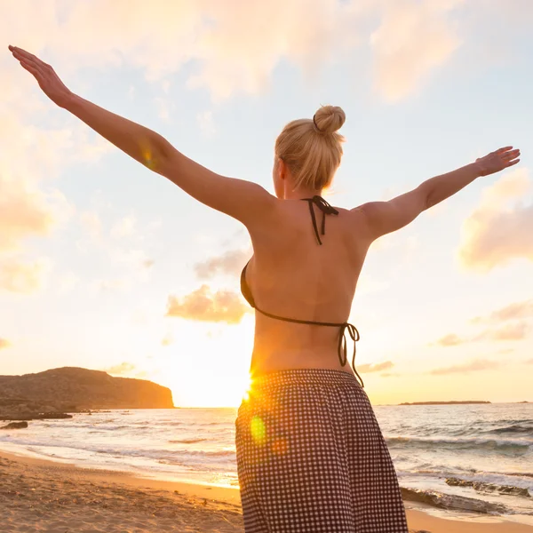 Freie glückliche Frau genießt Sonnenuntergang am Sandstrand — Stockfoto