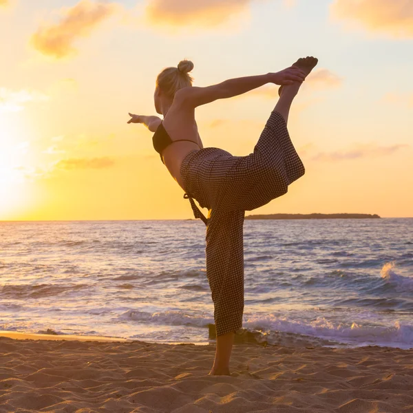 Kobieta ćwiczy jogę na plaży morskiej o zachodzie słońca. — Zdjęcie stockowe