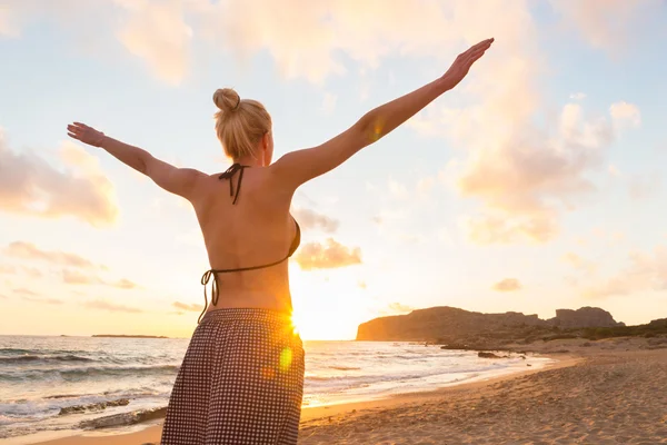 Freie glückliche Frau genießt Sonnenuntergang am Sandstrand — Stockfoto