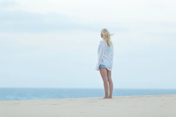 Donna sulla spiaggia di sabbia in camicia bianca . — Foto Stock