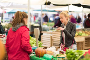 Kadın yerel gıda pazarından sebze alıyor..