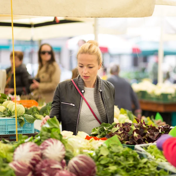 Woman buying vegetable at local food market.