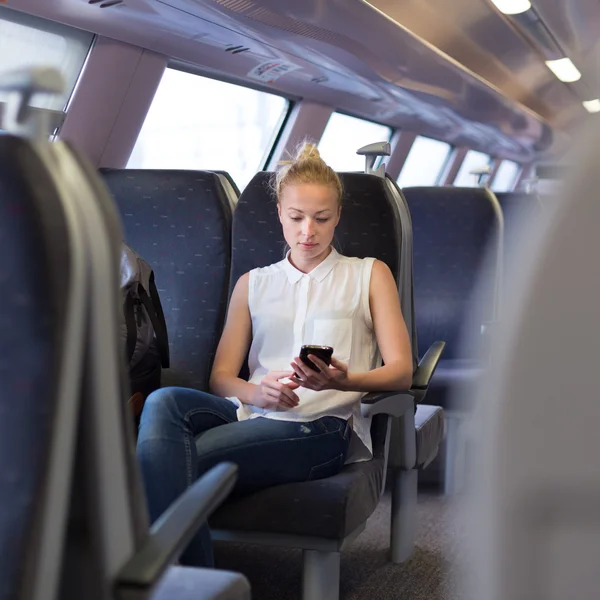 Mujer usando teléfono móvil mientras viaja en tren . — Foto de Stock