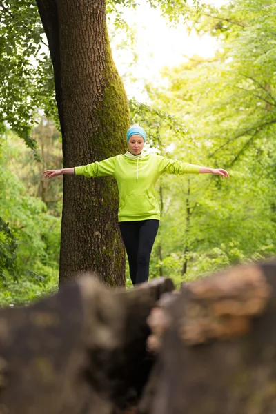 Mujer sosteniendo el equilibrio en el tronco del árbol en la naturaleza . —  Fotos de Stock