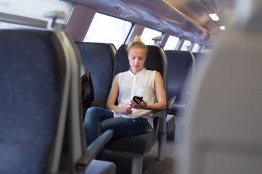 Trenle seyahat ederken cep telefonu kullanan kadın.