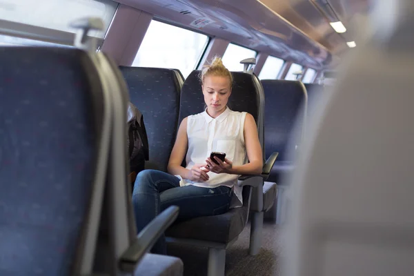 Trenle seyahat ederken cep telefonu kullanan kadın. — Stok fotoğraf