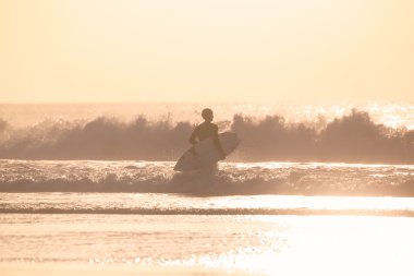 Sörfçü surfboard ile sahilde.