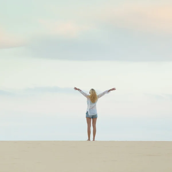 Fria kvinnan njuter frihet på stranden i skymningen. — Stockfoto