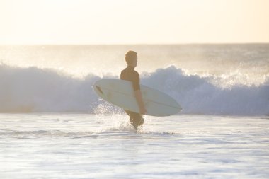 Sörfçü surfboard ile sahilde.