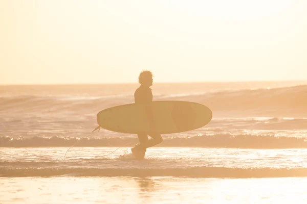 Silhouette eines Surfers am Strand mit Surfbrett. — Stockfoto