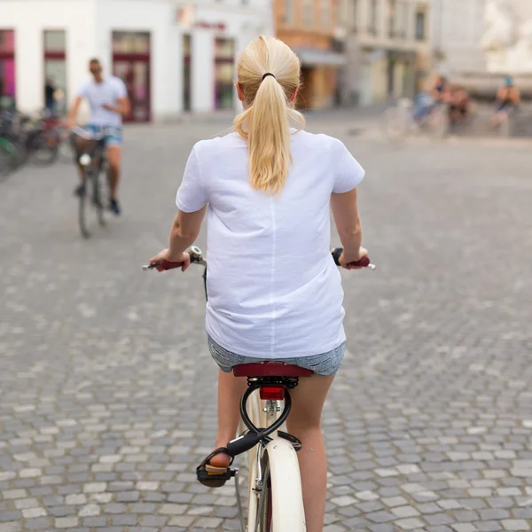 Beautiful blond caucasian woman riding bike in the city center — Stock Photo, Image
