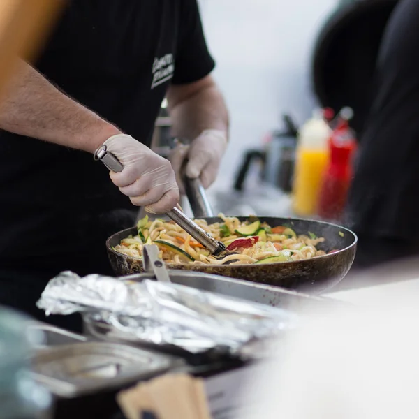 Asistent prodeje, vaření na venkovní pouliční food festivalu. — Stock fotografie