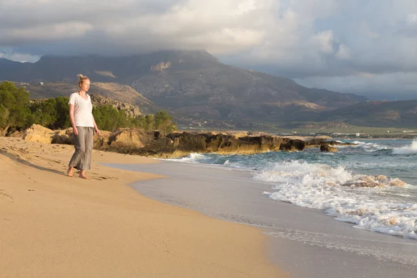 Woman walking on sand beach at golden hour — Stock Photo, Image