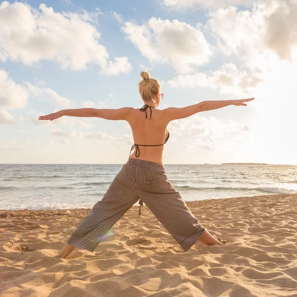 Femme pratiquant le yoga sur la plage de mer au coucher du soleil. — Photo