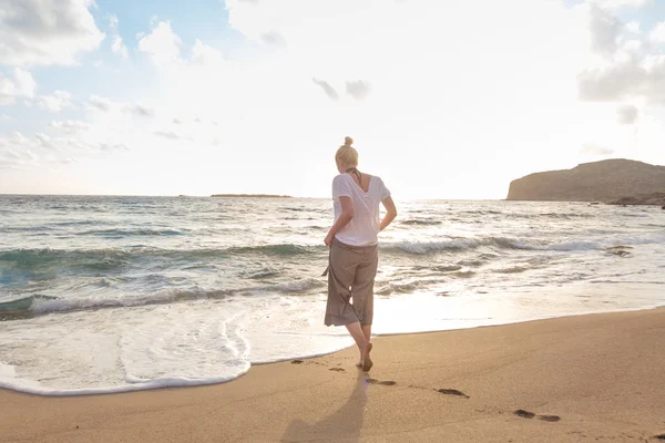 Altın saatinde kumsalda yürüyen bir kadın — Stok fotoğraf
