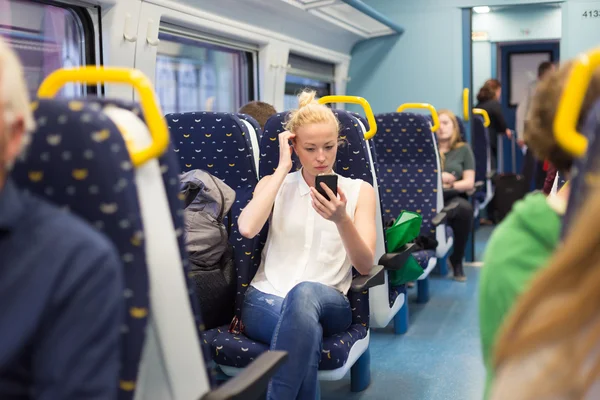 Kobieta przy użyciu telefonu komórkowego podczas podróży pociągiem. — Zdjęcie stockowe