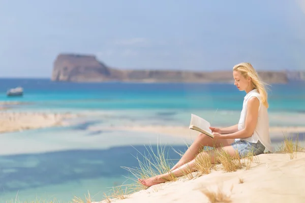 Женщина читает книгу, наслаждается солнцем на пляже . — стоковое фото