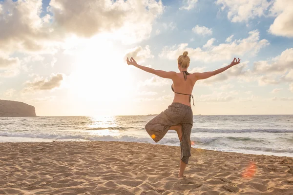 Mujer practicando yoga en la playa de mar al atardecer. —  Fotos de Stock