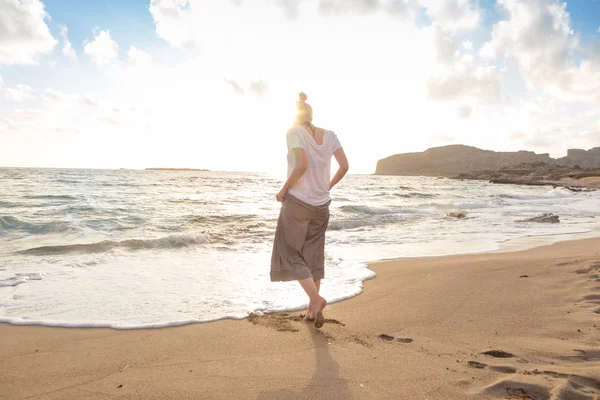 Woman walking on sand beach at golden hour — Stock Photo, Image