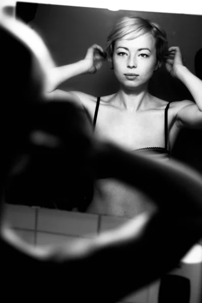 Femme se préparer pour le travail faisant routine de maquillage matin application maquillage et faire ses cheveux devant miroir de salle de bains à la maison. Image en noir et blanc — Photo