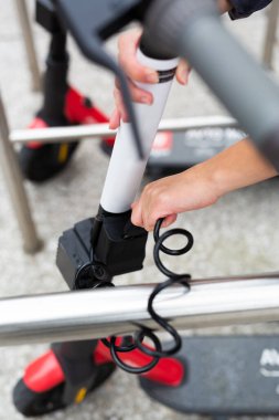 Kullanıcı elektrikli scooter 'ı güvenli bir şekilde park edip çitlere kilitliyor. Slovenya 'nın Ljubljana kentinde elektrikli scooterlarla ulaşımı paylaşma konsepti çevre dostu yeşil kentsel hareketlilik