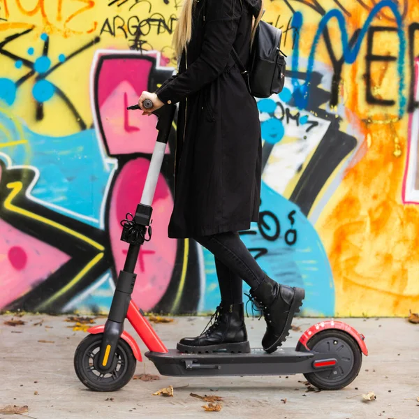 Trendy teenage girl riding public rental electric scooter in urban city environment at fall. New eco-friendly modern public city transport in Ljubljana — Stock Photo, Image