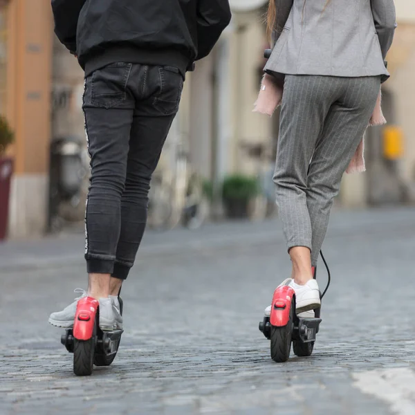 Vista trasera de los adolescentes irreconocibles de moda fashinable montar scooters eléctricos de alquiler público en el entorno urbano de la ciudad. Nuevo transporte público moderno ecológico en Liubliana, Eslovenia. — Foto de Stock