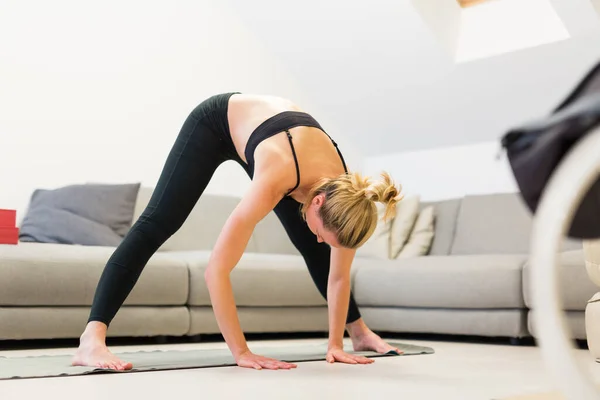 Piękna blondynka ćwicząca w domu. Kobieta ćwiczy jogę w domu. Fit girl za pomocą samouczków treningu dla zdrowego aktywnego stylu życia. Kobieta stosująca kwarantannę do treningu w domu. — Zdjęcie stockowe