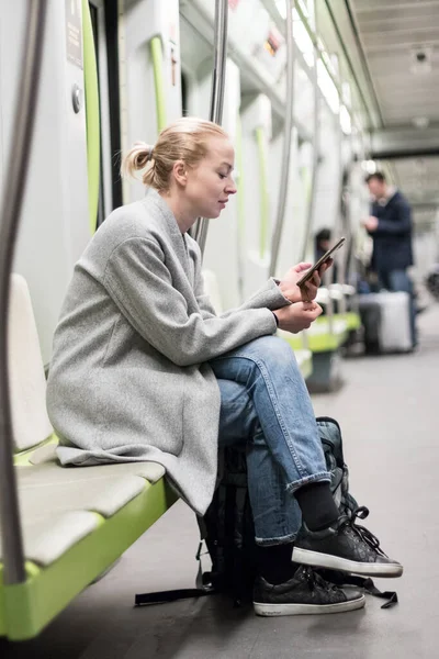 Portrait of lovely girl typing message on mobile phone in almost empty public subway train. Staying at home and social distancing recomented due to corona virus pandemic outbreak — Stock Photo, Image