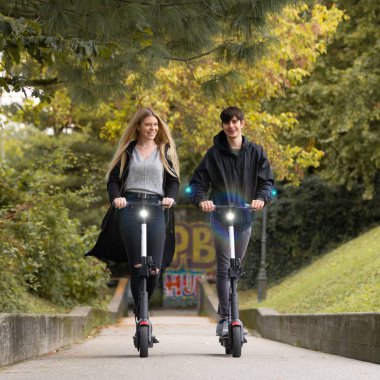 Şehir parkında kiralık elektrikli scooterlara binen modaya uygun gençler. Slovenya 'nın Ljubljana kentindeki yeni çevre dostu modern kamu taşımacılığı